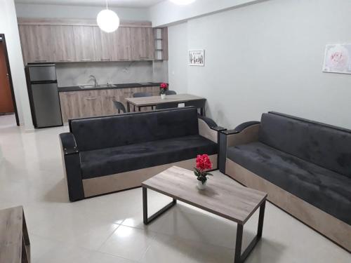 ein Wohnzimmer mit zwei schwarzen Sofas und einem Tisch in der Unterkunft Disy Apartments in Vlorë