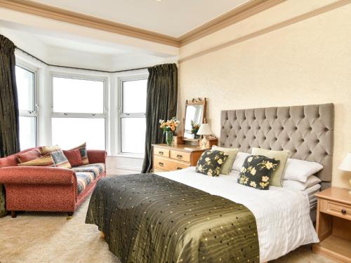 1 dormitorio con cama extragrande y sofá en Wavecrest, en Pwllheli