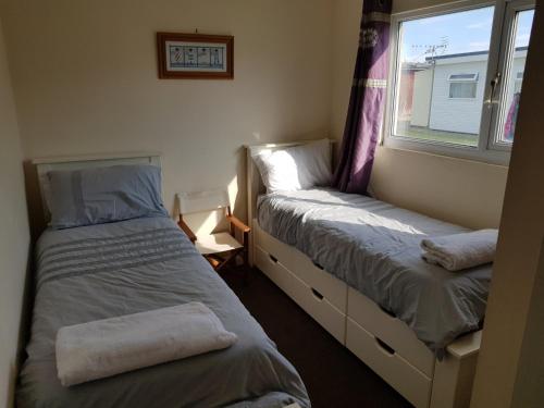 2 camas en una habitación pequeña con ventana en Camber Sands Holiday Chalets - The Grey en Camber
