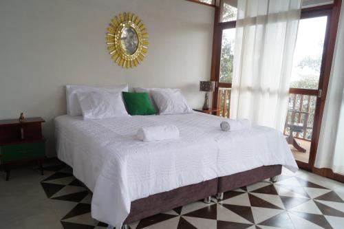 1 dormitorio con 1 cama blanca grande y espejo en la pared en Indano Art Lodge, en Lamas