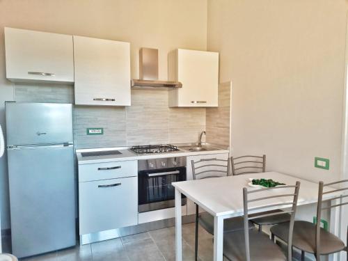 阿爾布斯的住宿－Monolocale Arbus R0478，一间厨房,配有白色家电和桌椅