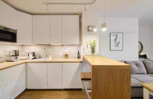 a kitchen with white cabinets and a couch at Apartament Green Park, Polanica Residence, garaż podziemny & mini SPA & Rowery in Polanica-Zdrój