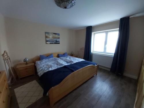 a bedroom with a bed with blue sheets and a window at Ferienwohnung Schneifelsicht in Auw