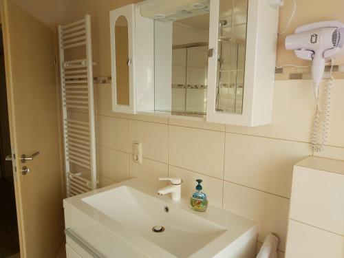 uma casa de banho com um lavatório branco e um espelho. em Ferienwohnung Schneifelsicht em Auw
