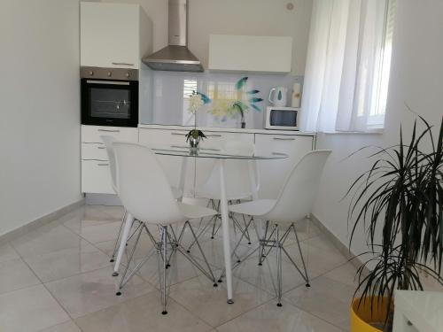 une cuisine avec une table en verre et des chaises blanches dans l'établissement Sweet Apartments, à Split