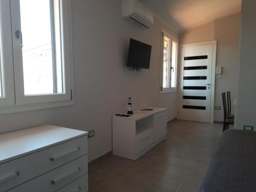 een witte slaapkamer met een wastafel en een tv aan de muur bij Monolocale Arbus R0478 in Arbus