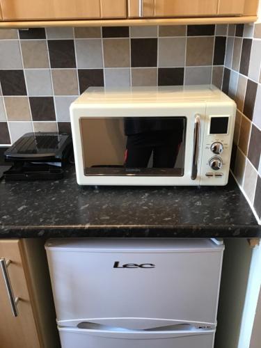 a white microwave sitting on top of a refrigerator at Largs Holiday Apartment in Largs