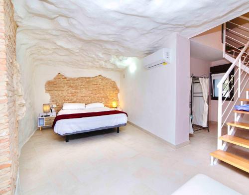 1 dormitorio con 1 cama con pared de piedra en Casa Rural Las Colmenas, en Alcalá del Júcar