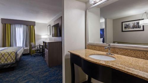 a hotel room with a bathroom with a sink and a bed at Best Western Knoxville Airport / Alcoa, TN in Alcoa