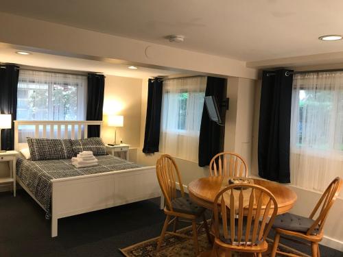 Cambie Lodge في فانكوفر: غرفة نوم بسرير وطاولة وكراسي