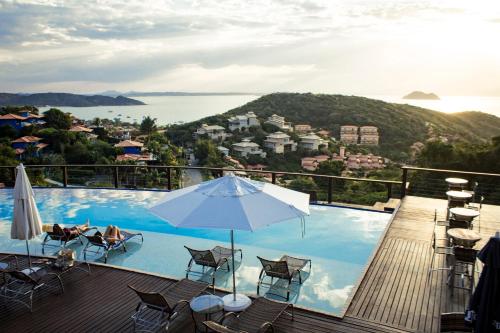 a pool with chairs and an umbrella on a deck at Eny Boutique Hotel & Spa in Búzios