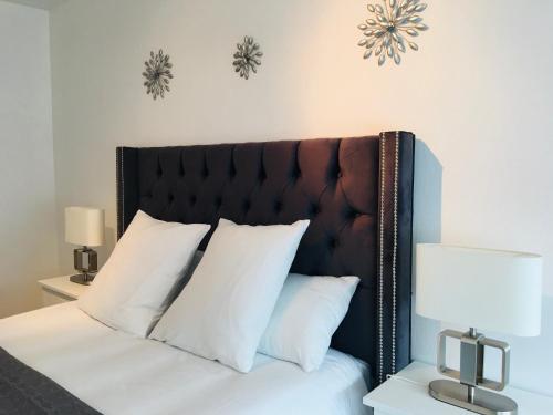 - un lit avec une tête de lit noire et des oreillers blancs dans l'établissement Magnifique Appartement au cœur de Nancy, à Nancy