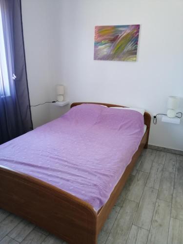a bed in a room with a purple blanket on it at Apartmani Nevera in Krk
