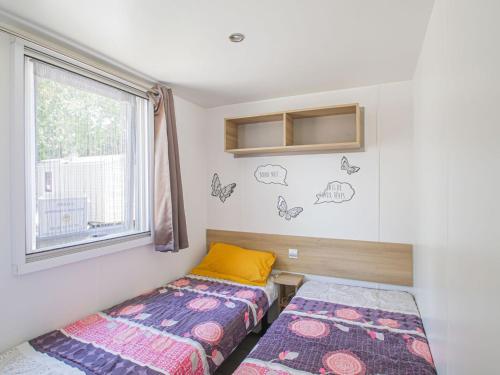 une chambre avec deux lits et une fenêtre dans l'établissement Mobile Home in Saint-Jean near Beach & Pool, à Saint-Jean-de-Monts