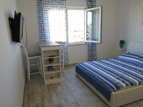 a bedroom with a bed and a desk and a television at Apartmani Nevera in Krk