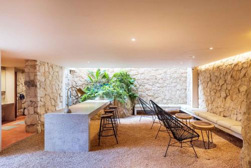 a living room with a stone wall and a table and chairs at Sessile Tulum by The Spot Rentals in Tulum