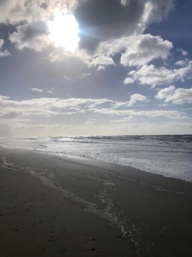 a sandy beach with the ocean and the sun at Casa rosa - se reserva con seña in Barra del Chuy