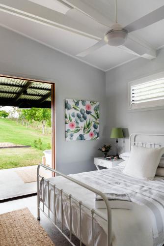 a bedroom with a white bed and a window at Thirlestane Farm Cottage & Barn in Cooroy