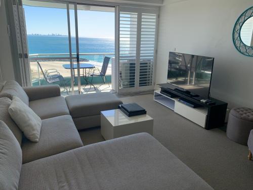 sala de estar con sofá y TV de pantalla plana en Ocean Plaza Resort, en Gold Coast