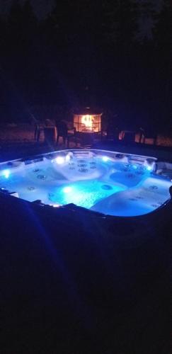 a hot tub with lights in a yard at night at GÎTE SUR L'ARC EN CIEL in Saint Adrien