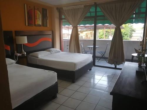 a bedroom with two beds and a balcony with a table at Hotel Tradicional Savaro SA de CV in Zihuatanejo