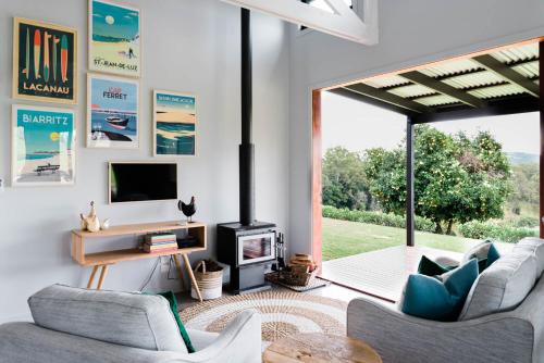 a living room with two chairs and a tv and a fireplace at Thirlestane Farm Cottage & Barn in Cooroy