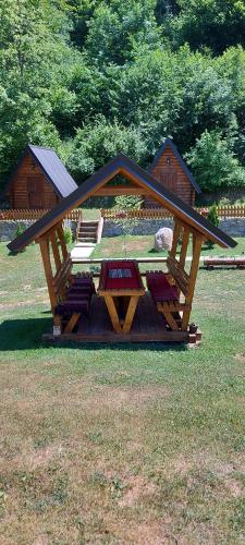 a wooden gazebo with a picnic table in the grass at Gradine - Katun kamp in Plav