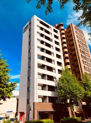 a tall white building with trees in front of it at Dream Inn Hakata in Fukuoka