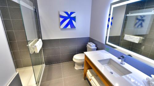 La salle de bains est pourvue de toilettes, d'un lavabo et d'un miroir. dans l'établissement Holiday Inn Express & Suites Vaudreuil-Dorion, an IHG Hotel, à Vaudreuil-Dorion