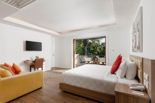a white bedroom with a bed and a couch at Downtown Villas in Seminyak