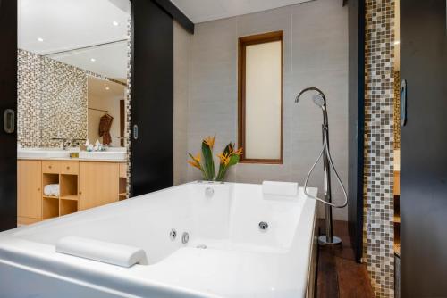 a bathroom with a white tub and a mirror at Downtown Villas in Seminyak