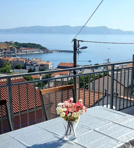 a table with a vase of flowers on a balcony at LOVELY APARTMENTS Senj - Spectacular Sea View & Free Parking & WI-FI in Senj