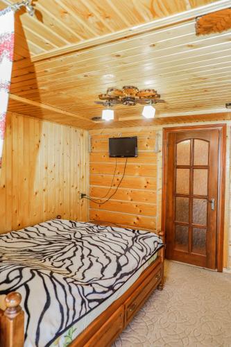 a bedroom with a bed and a tv on the wall at Котедж "У Бойка" in Mykulychyn