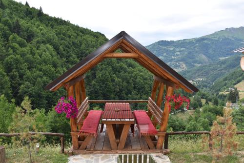 a gazebo with benches and a table with flowers at Gradine - Katun kamp in Plav