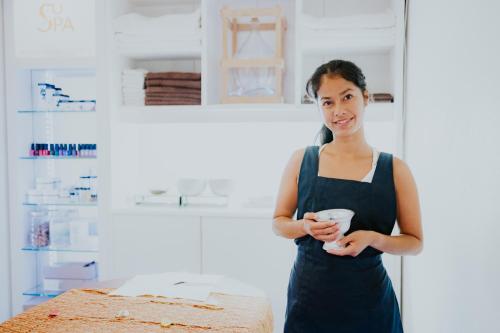 a woman standing in a kitchen holding a cup at HEIMATEL - Suiten, Apartments und Studios in Scheidegg