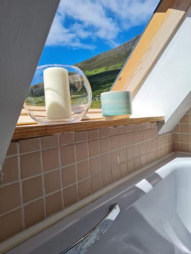 a bathroom with a window with a sink and a tub at Sea to Summit Cottage in Slievemore