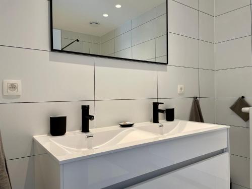 a white bathroom with a sink and a mirror at Vakantiehuis Sahara119 in Lommel