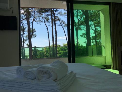 a pile of towels on a bed in front of a window at Magnetiti Hotel in Ureki