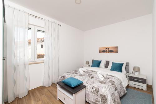 a white bedroom with a bed and a window at Apartman Palada in Žminj
