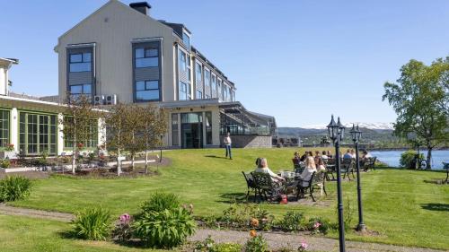 a group of people sitting on a lawn in front of a building at Fru Haugans Hotel in Mosjøen
