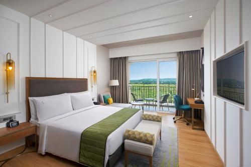 a hotel room with a bed and a balcony at Holiday Inn Goa Candolim in Candolim