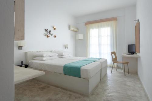 a white bedroom with a bed and a television at Hotel 28 in Kamari