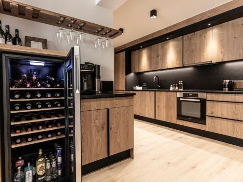 a kitchen with wooden cabinets and a refrigerator at FRAU GANS - pure mountain apartments in Saalbach Hinterglemm