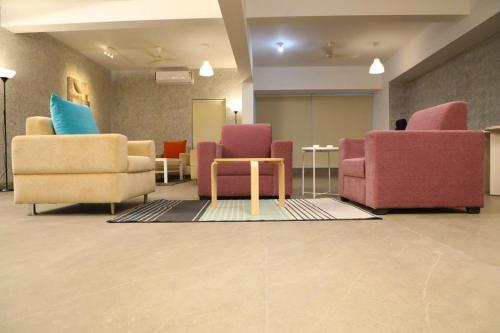 a lobby with three chairs and a table in a room at SwanSuites Gachibowli in Hyderabad