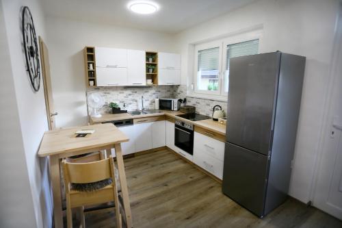 a kitchen with a stainless steel refrigerator and a wooden table at Centrum Apartman Kőszeg in Kőszeg