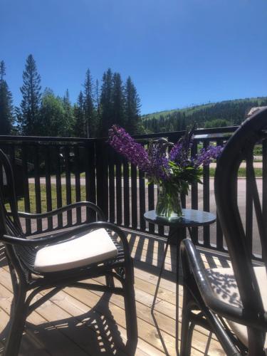 two chairs and a table with a vase of flowers on a deck at Hotell Viktors in Sälen