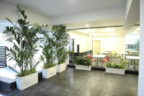 a room with potted plants and tables and chairs at SwanSuites Gachibowli in Hyderabad