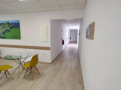 a room with a glass table and chairs and a hallway at Las Huertas in La Penilla