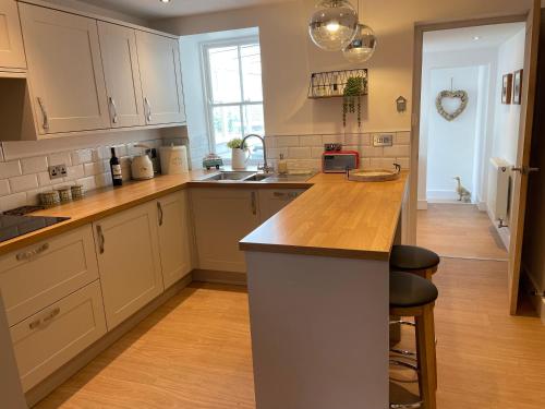 cocina con armarios blancos y encimera de madera en St Reatham Cottage en Kilmington