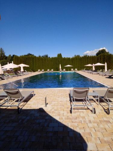 a swimming pool with lounge chairs and umbrellas at Gut Drasing in Krumpendorf am Wörthersee